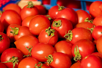 Closeup of Fresh Red Plum Tomatoes with Stems in Basket at Farmers Market Produce Stand, Vibrant Color and Texture
