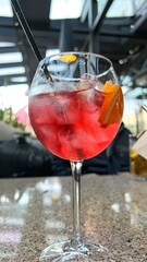 Refreshing Red Cocktail with Ice Cubes and Orange Slice on Bar Counter, Summer Drink