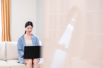 家でリラックスをしてパソコンを使う若い女性