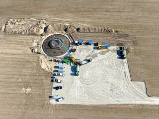 Luftbild der Erstellung des Fundaments einer Windkraftanlage mit Betonmischern und Betonpumpen,...