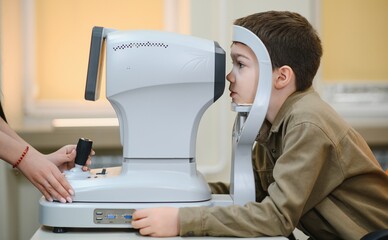 Obraz premium Ophthalmologist examining eyesight of child with autorefractor in clinic