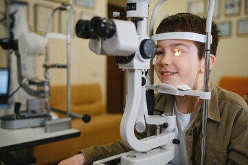 Boy undergoing eyesight examination with slit lamp biomicroscope in ophthalmology clinic