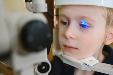 Boy undergoing vision diagnostics with modern ophthalmic equipment in clinic