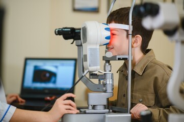 Child undergoing eyesight examination with ophthalmological equipment in clinic