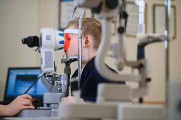 Child undergoing eyesight examination with ophthalmological equipment in clinic