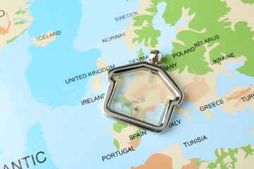 Metal house figure on world map, closeup