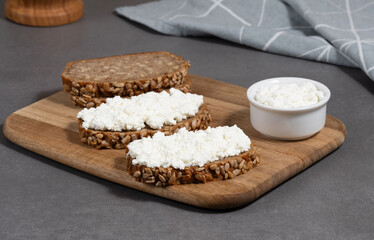 Delicious rye bread topped with cottage cheese on a wooden board in a modern kitchen setting