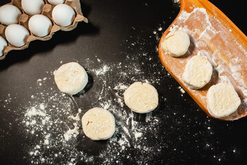 Process of making syrniki. Form round syrniki from curd dough. Top view on black surface. Russian cuisine.