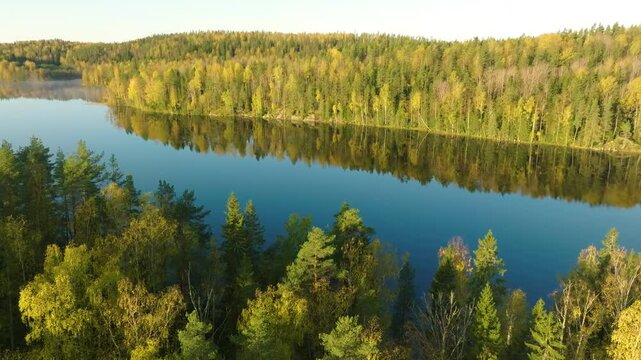 Aerial view of Aulanko Nature Reserve in H&auml;meenlinna, Finland, featuring a serene lake surrounded by colorful autumn forests.