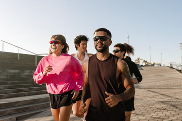 The young athletes run outdoors in the morning on a paved urban path. They wear athletic clothing...