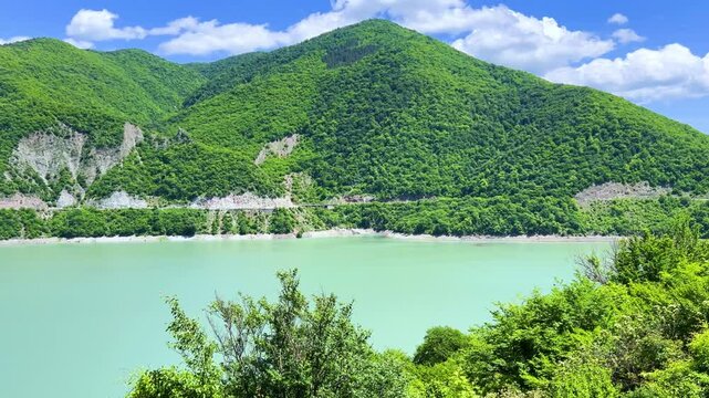 The Zhinvali reservoir, the lake landscape with mountains, the main Caucasian ridge, the Georgian military road. Georgia. An artificial reservoir. Blue sky with white clouds. 4К