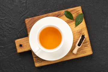 Cup of tea with dry and fresh leaves on concrete background, top view