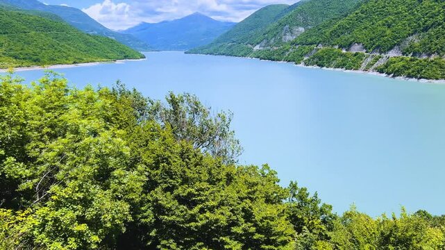 The Zhinvali reservoir, the lake landscape with mountains, the main Caucasian ridge, the Georgian military road. Georgia. An artificial reservoir. Blue sky with white clouds. 4К