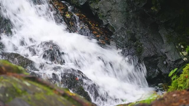 Aerial drone views of Belye Mosty Waterfall flowing powerfully amid vibrant autumn forest colors and rocky cliffs in the Russian wilderness.