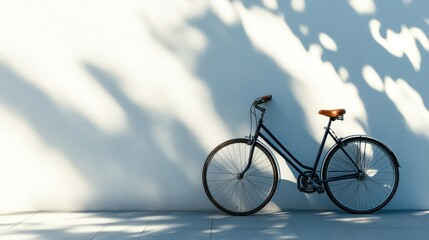 Fototapeta premium Dark bicycle leaning on wall with sunlight shadow