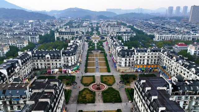 Aerial Shot Of Residential Buildings In City By Mountains, Drone Flying Forward Over Park - Hangzhou, China