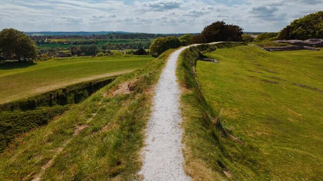 Weathered earthwork banks and ruined foundation stones punctuate the windswept summit of Old Sarum, Salisbury, Wiltshire, England, UK