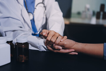 female doctor or woman medical staff holding hand, working hand in hand, giving encouragement to patient or relative of patient; concept of woman health care worker, doctor, therapist, medical worker