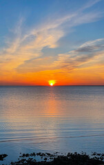 Bright sunset with yellow sun under water surface. Serene sunset over the sea. Summer evening. Vertical photography.