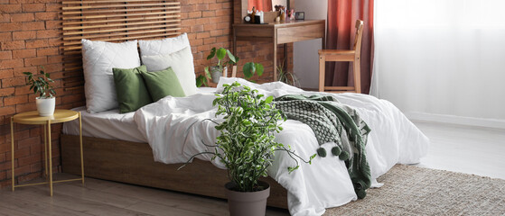 Wooden dressing table and bed near brick wall in interior of bedroom