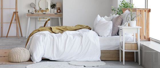 Interior of bedroom with dressing table and bed near white wall