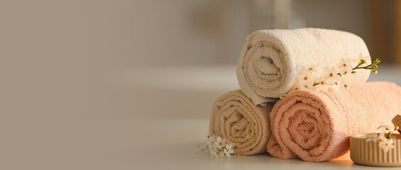 Clean towels with blossoming branches on table in bathroom. Banner for design