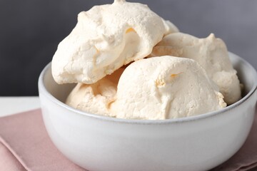 Delicious homemade meringue cookies in bowl on table, closeup