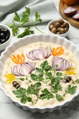 Raw focaccia with vegetables and olives on white marble table, closeup