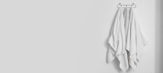 Clean soft towels hanging on light wall in bathroom. Banner for design