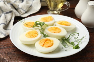Boiled eggs and microgreens on wooden table, closeup