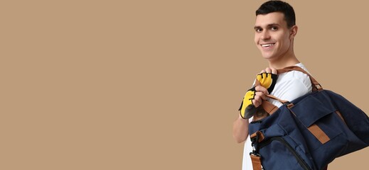 Young man with sports bag on beige background with space for text
