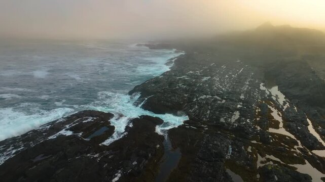 This aerial footage shows the rugged rocky coastline at Lastras de Pechon in Cantabria, Spain, where ocean waves crash dynamically against the shore.