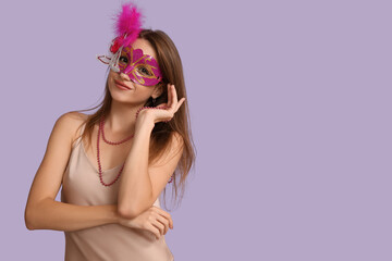 Pretty young woman in carnival mask on lilac background