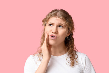 Beautiful young woman suffering from toothache on pink background