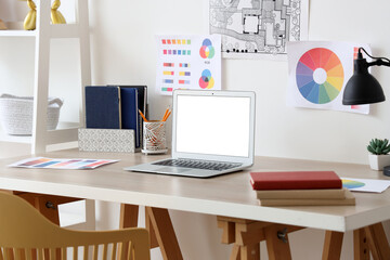 Workplace with blank laptop in light room