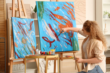 Female artist with palette painting on canvas in workshop