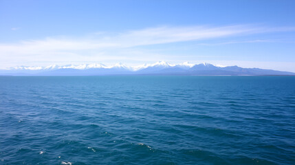 Obraz premium large open water surface with far snowcapped mountain range on the horizon at sunny day.
