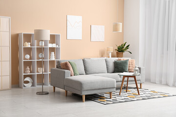 Cozy sofa, coffee table with lantern and book in interior of living room