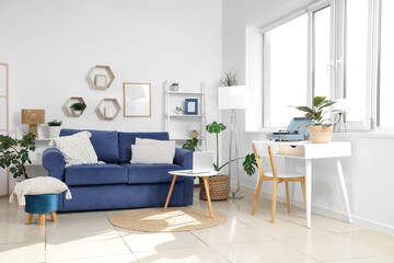 Comfortable sofa and coffee table with laptop in interior of living room