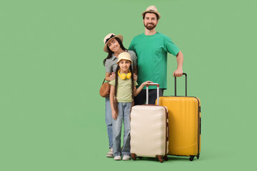 Smiling family of tourists with hats and suitcases on green background