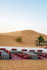 Tent camp for tourists in Al Khatim Desert. Abu Dhabi, United Arab Emirates. Bedouin resting place in sand dunes. Colorful traditional African rugs and pillows on the ground. Travel concept