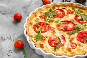 Delicious tomato tart with arugula leaves on grey background, closeup
