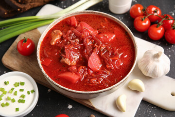 Bowl of tasty Ukrainian borscht and ingredients on black background, closeup