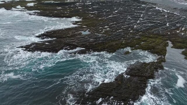 Aerial drone shot capturing the distinct flysch layers of sedimentary rocks forming along the coastal edge of Cape Nemetsky, Vaida Bay