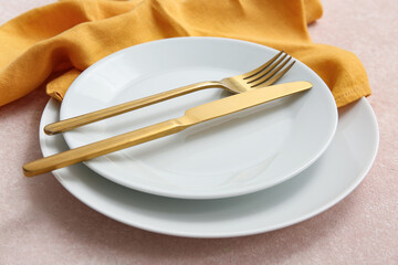 Beautiful table setting with golden cutlery on beige background, closeup