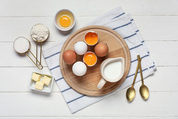 Composition with ingredients for baking and spoons on light wooden background