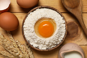 Composition with plate of flour, fresh chicken eggs, milk and spikelets on wooden background