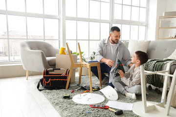 Father and his son with drill assembling furniture at home