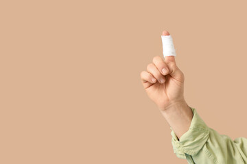 Male hand with bandaged finger on beige background