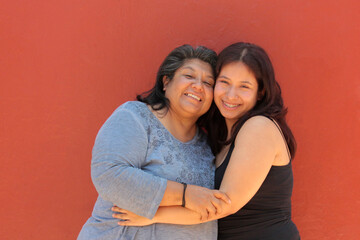 A 50-year-old Latina mother and her 18-year-old daughter hug and kiss each other to show their love and celebrate Mother's Day